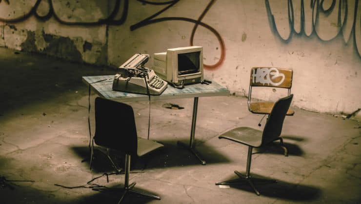 Sedie da ufficio e una scrivania su cui sono presenti un computer ed ua macchian da scrivere.