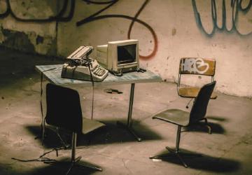 Sedie da ufficio e una scrivania su cui sono presenti un computer ed ua macchian da scrivere.