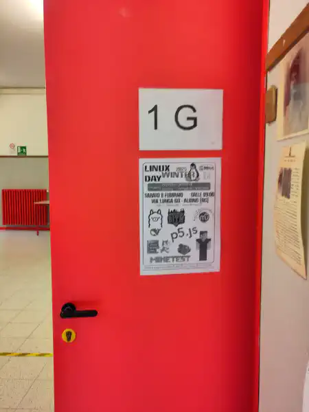 Foto di una porta della prima G in cui è appeso un poster del Linux Winter Day